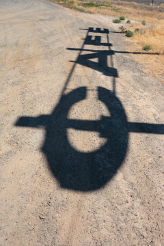 Shadow of an old sign on dry ground, outline of a C and A letters. 