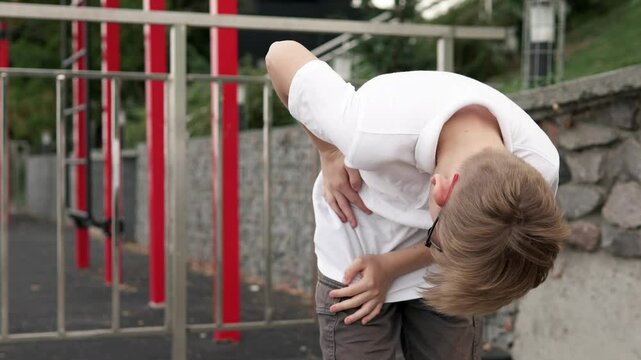 The guy feels a sharp pain in the side in the liver area during an outdoor workout. The concept of sports and injuries.
