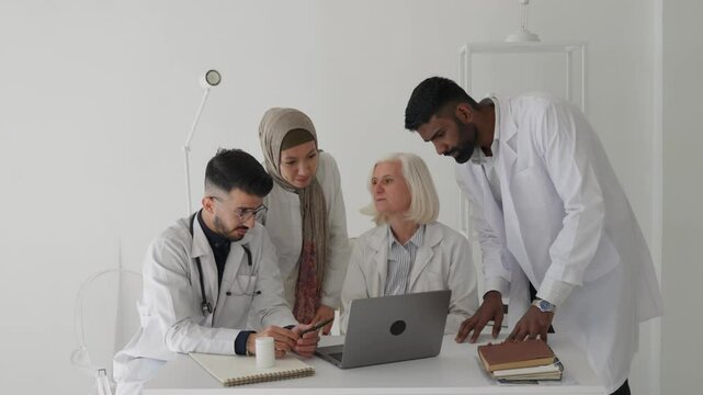 An elderly doctor in the office, talking with young interns doctors, discussing the patient's condition and his further treatment, through discussion they come to a consensus regarding the diagnosis 