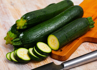 Close-up of fresh green zucchini cut on wooden desk in kitchen