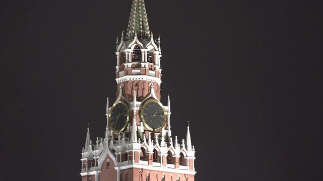 Moscow December 10 2022. A tall red and white tower with two clocks on it. The clock faces are black and the tower is lit up at night