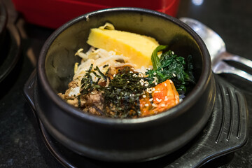 Traditional Korean Bibimbap in a Hot Stone Bowl with Fresh Vegetables, Egg, and Seaweed Garnish