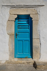 Old textured blue door in a white wall in Greece