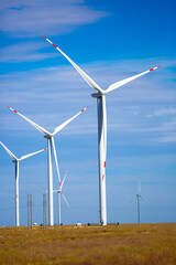 Fleet of power generators in motion. The blades of the wind farm rotate against the sky. The...