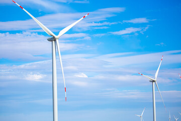 Fleet of power generators in motion. The blades of the wind farm rotate against the sky. The concept of extracting electricity from renewable sources. Wind turbine to generate electricity.