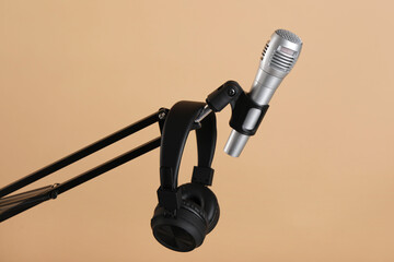 Stand with microphone and headphones on beige background. Sound recording and reinforcement