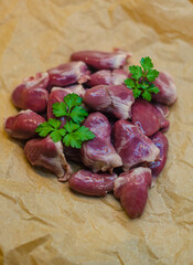 Raw duck hearts with parsley on beige baking paper in kitchen. High quality photo