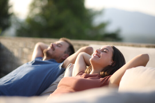 Happy couple relaxing in a terrace sofa