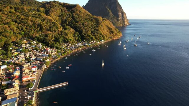 Aerial Drone Footage Captures Stunning Views Of Housing On Hills Near Gros Piton, St. Lucia. The Camera Pans Over The Caribbean Sea, Revealing Boats And A Vibrant Sunset Atmosphere.