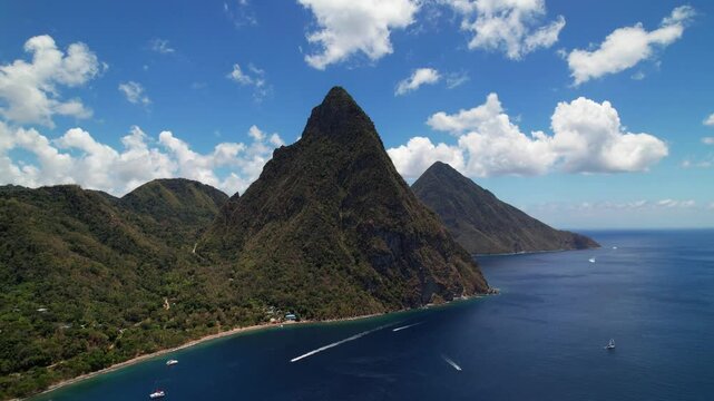 Aerial Drone Footage Captures Gros Piton In St. Lucia, Showcasing Its Lush Greenery And Majestic Presence. Small Boats Navigate The Vibrant Caribbean Sea Under A Sunny Sky.