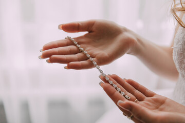 A woman is holding a necklace in her hands. The necklace is made of diamonds and is very shiny. The...