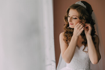 A woman is getting ready for her wedding and is putting on her wedding dress. She is wearing a...