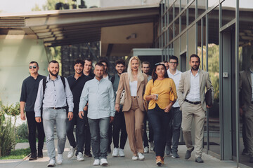 A diverse group of businessmen and colleagues walking together by their workplace, showcasing collaboration and teamwork in the company.