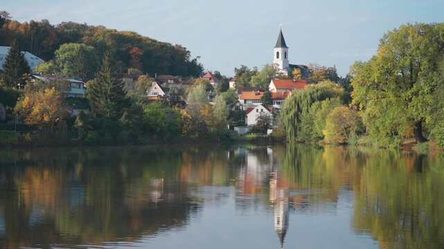 St. Sebastian's and Fabian's Church in Prague stands above the lake surrounded by greenery and small tidy houses.