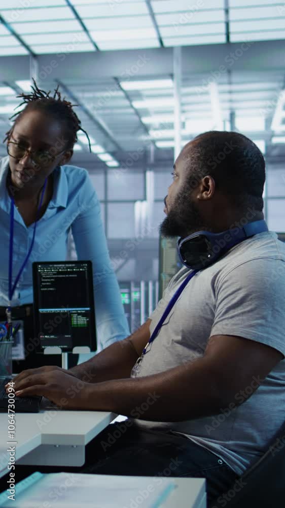 Poster engineer working with colleague on computer in high tech data center establishment monitoring hardwa