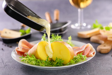 raclette cheese melting on potato with ham and white wine glass