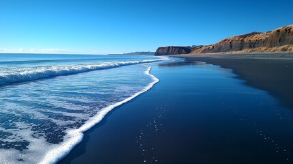 Tranquil Beach with Waves and Cliffs under Clear Blue Sky