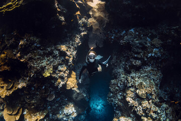 Freediver woman emerges from the underwater cave in tropical sea on Menjangan island. Freediving in...