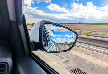 A View Looking Into The Side Mirror Of A Vehicle As It Travels Along A Highway