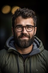 Obraz premium Close up portrait of a young man with a beard and glasses looking directly at the camera