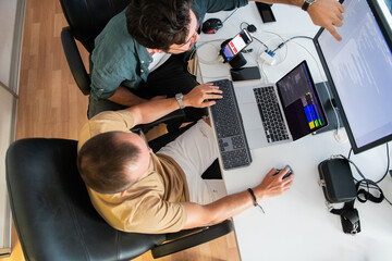Top view of programmer diligently testing smartphone applications while sitting in their office.