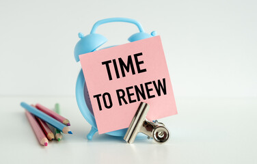 A blue alarm clock with a pink note that says Time to Renew