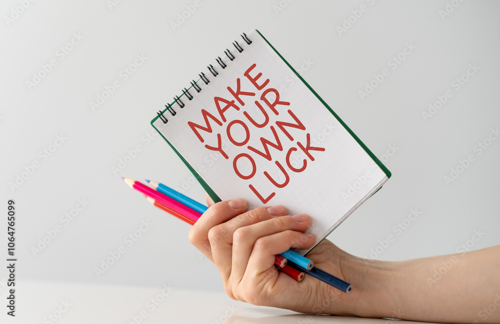 Poster a person is holding a notebook with the words make your own luck written on it