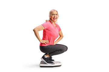 Happy middle aged woman weighing on a scale