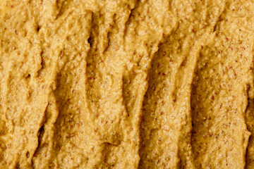 Mustard sauce with grains close-up. Hot spices as a background. Texture of Dijon mustard.