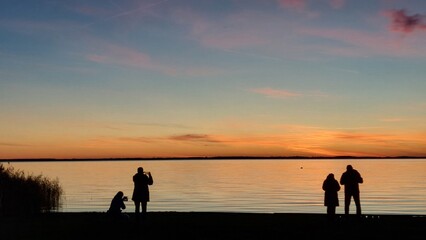 Touristen machen Handy-Fotos vom Sonnenuntergang zur blauen Stunde am Meer 