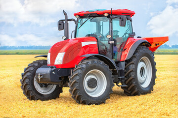 Obraz premium Powerful red tractor in vast wheat field under blue sky, showcasing modern agricultural machinery concept