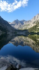 A pristine lake surrounded by mountains, perfectly reflecting the peaks and sky in calm, mirror-like water, creating a tranquil scene.