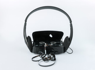 Audio cassette player with headphones and an open cassette compartment cover from which a magnetic...
