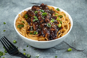 Teriyaki Grilled Chicken Noodles with green onion, and fork served in bowl isolated on grey background side view of asian food