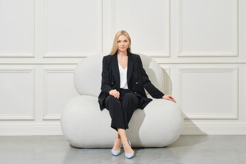 Confident businesswoman in pantsuit sits on bean bag