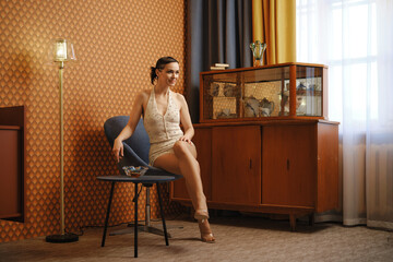 Elegant woman in vintage body suit sits in old-fashioned interior