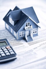 An office setting with property loan documents, a calculator, and a small house model on the desk. The clean backdrop provides ample copy space for additional elements.