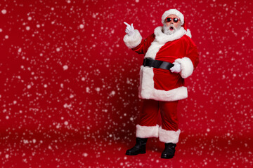 Photo of excited crazy man indicate finger empty space novelty wear santa hat costume isolated red color background