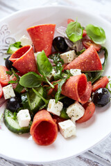 Salad with Salami, Feta Cheese, Black Olives, Cucumber and Cherry Tomatoes. Close up.