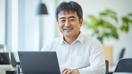 Fototapeta premium Confident Middle Aged Asian Businessman Smiling While Working on Laptop in Office