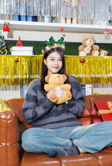 Cheerful young beautiful asian women. Cute female smiling wearing deer horns and long sleeve knitted sweater sitting on sofa posing enjoy at party, Happy New Year celebration Christmas holiday concept