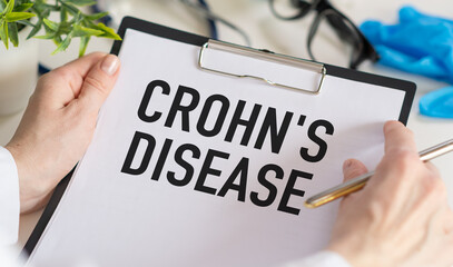 Paper with CROHN'S DISEASE on the office desk, stethoscope and pills, top view