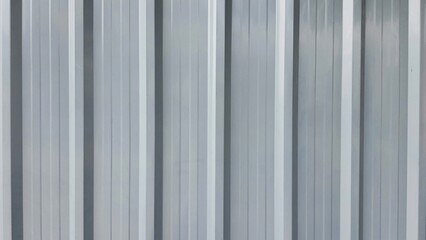 Close-up of an industrial material in a vertical line of metal sheets. A warehouse wall in an industrial area. Silver metal sheet.