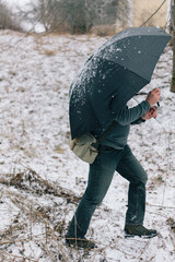 Man Walking Through Snow with Black Umbrella