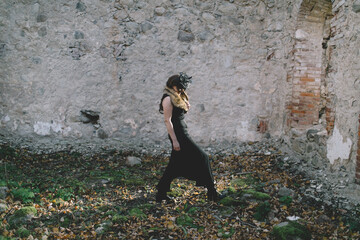 Woman in Black Dress Walking by Stone Wall
