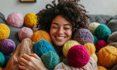 A joyful woman embraces colorful wool balls while surrounded by soft textures in a cozy indoor space