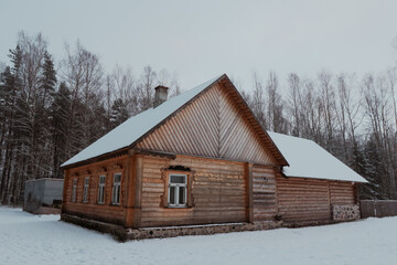 Traditional wooden house in snowy Estonia surrounded by tall trees in winter season