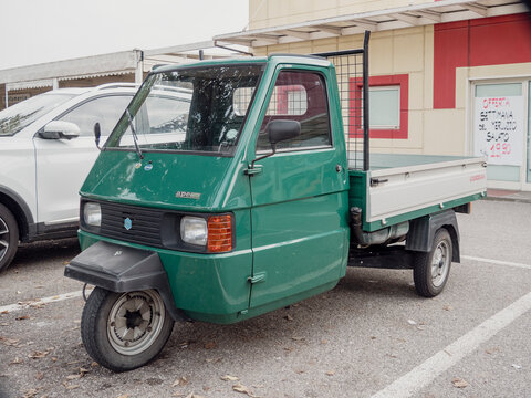 Green ape piaggio parked near a supermarket in italy
