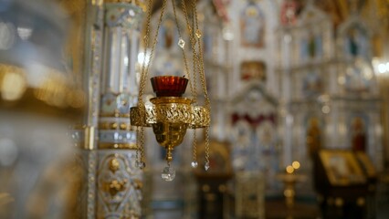 Hanging red glass and gold oil lamp illuminates church interior