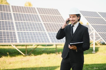 Portrait of a successful businessman or engineer inspecting the operation of solar panels. The...
